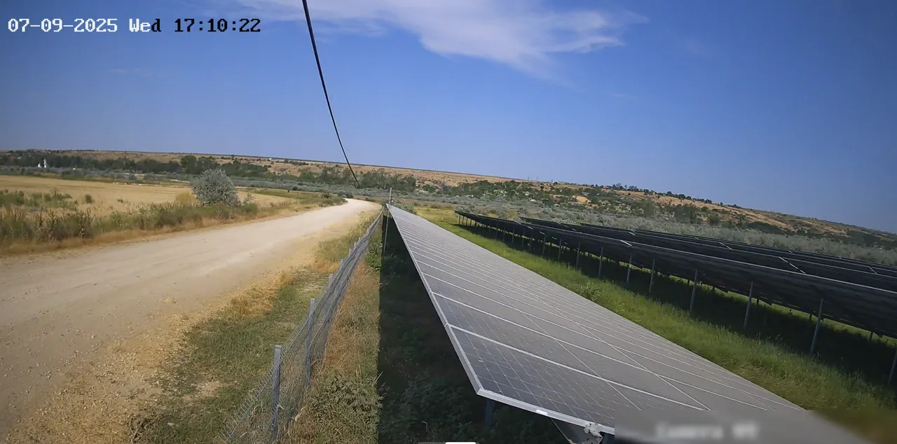 Cameră de supraveghere la un parc fotovoltaic: panourile și drumul de lângă gard